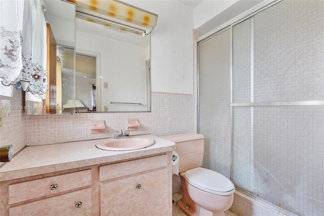 full bathroom featuring a stall shower, toilet, a wainscoted wall, vanity, and tile walls