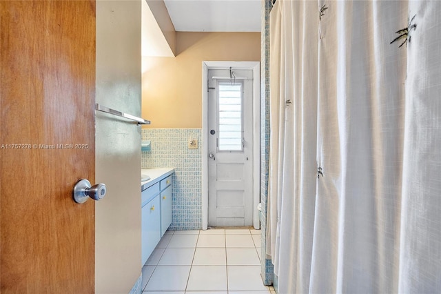 bathroom with tile patterned flooring, a wainscoted wall, tile walls, and vanity