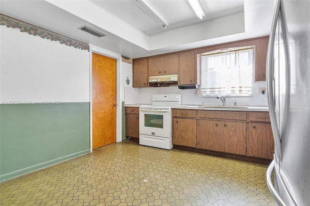 kitchen with a sink, light floors, white electric range, and freestanding refrigerator