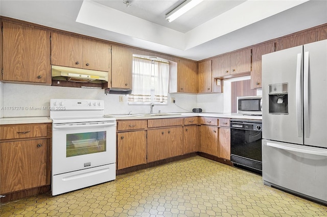 kitchen with under cabinet range hood, a sink, light countertops, appliances with stainless steel finishes, and light floors