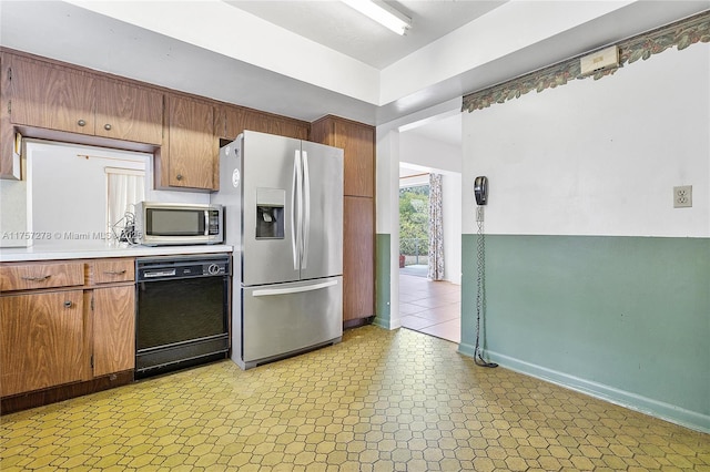 kitchen with appliances with stainless steel finishes, baseboards, light countertops, and light floors