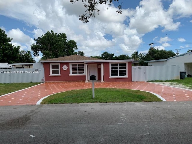 view of front facade featuring stucco siding, a gate, fence, and a front yard