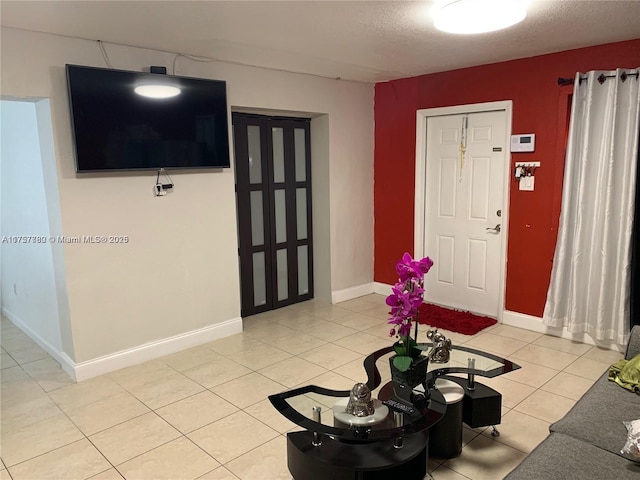 unfurnished living room featuring light tile patterned floors, a textured ceiling, and baseboards