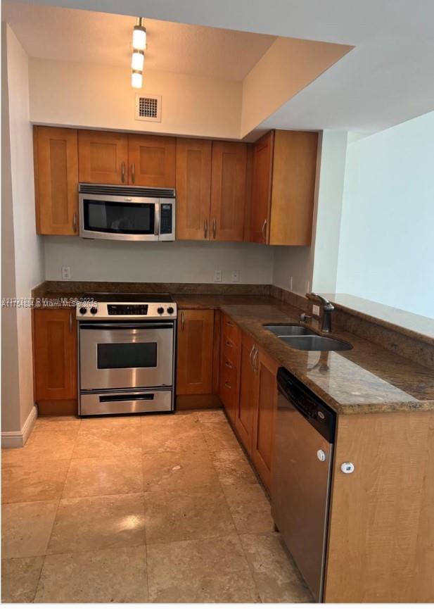 1745 E Hallandale Beach Blvd Unit 804W, Hallandale Beach, FL 33009 - kitchen featuring stainless steel appliances, brown cabinets, a sink, and a peninsula