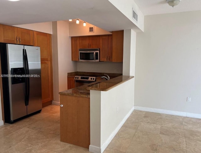 1745 E Hallandale Beach Blvd Unit 804W, Hallandale Beach, FL 33009 - kitchen featuring stainless steel appliances, brown cabinetry, dark stone counters, a peninsula, and baseboards