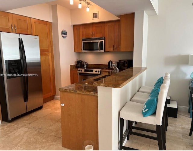 1745 E Hallandale Beach Blvd Unit 804W, Hallandale Beach, FL 33009 - kitchen featuring stainless steel appliances, brown cabinetry, dark stone countertops, and a sink