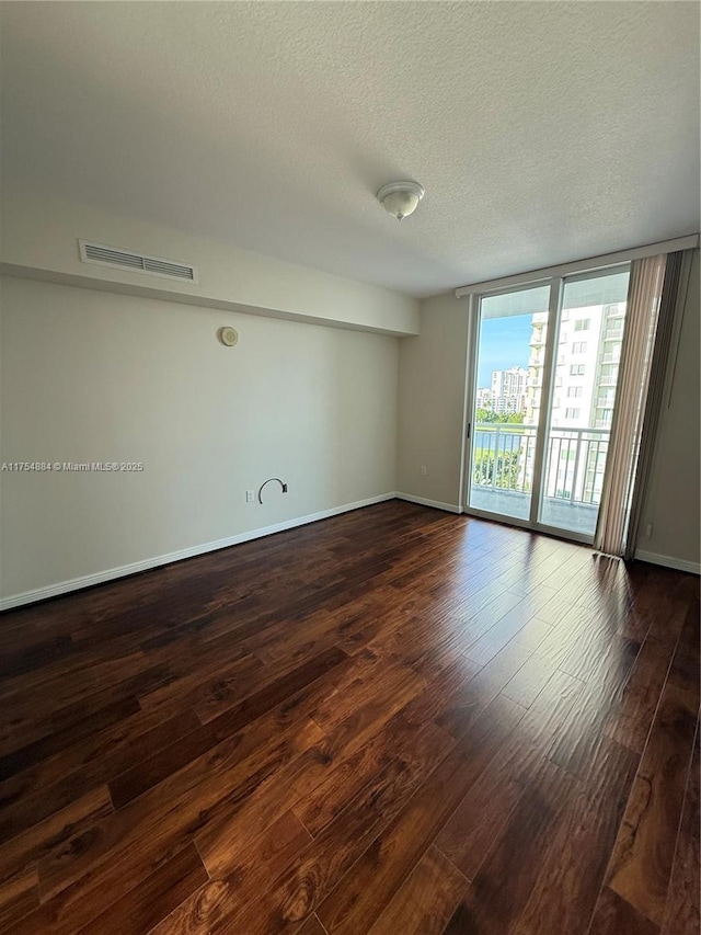 1745 E Hallandale Beach Blvd Unit 804W, Hallandale Beach, FL 33009 - spare room featuring a textured ceiling, dark wood-style flooring, a wall of windows, and baseboards