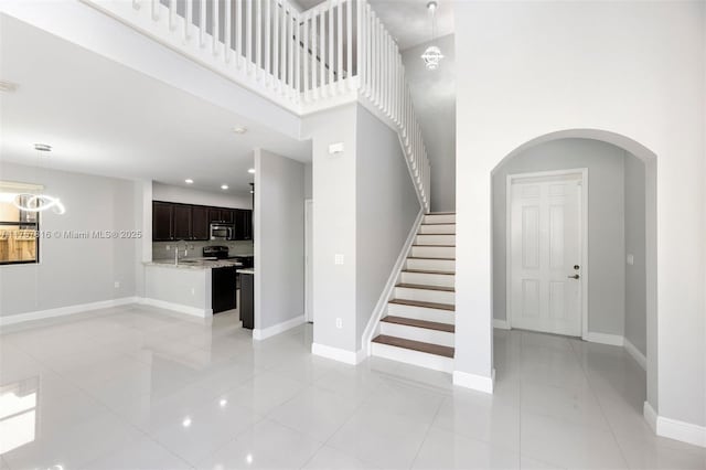 interior space featuring stairway, a high ceiling, baseboards, and light tile patterned floors