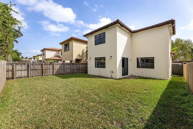 rear view of house featuring stucco siding, a fenced backyard, and a yard