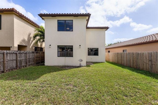 back of house featuring a lawn, a fenced backyard, and stucco siding