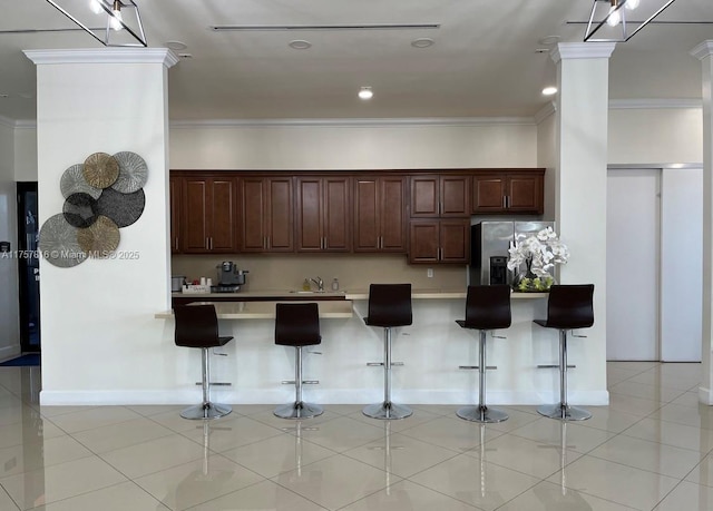 kitchen with ornamental molding, stainless steel refrigerator with ice dispenser, and light tile patterned floors