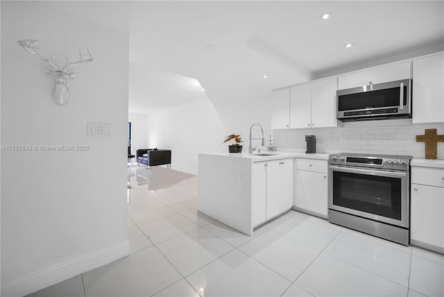 kitchen featuring stainless steel appliances, decorative backsplash, white cabinetry, a sink, and a peninsula