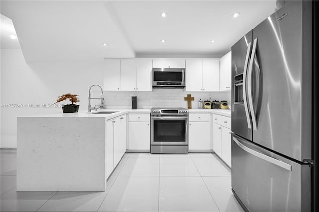 kitchen featuring decorative backsplash, appliances with stainless steel finishes, a peninsula, light countertops, and a sink