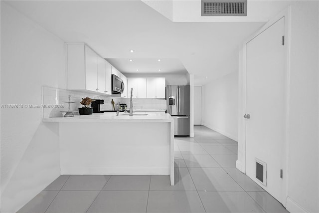 kitchen featuring a peninsula, appliances with stainless steel finishes, light countertops, and visible vents