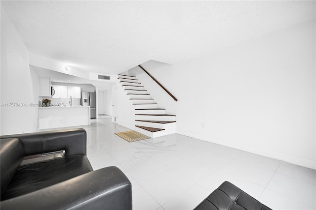 living room with baseboards, stairs, visible vents, and a textured ceiling