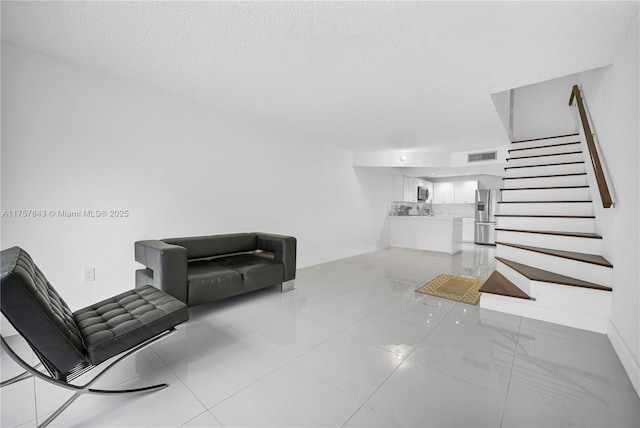 living room featuring a textured ceiling, stairway, and visible vents