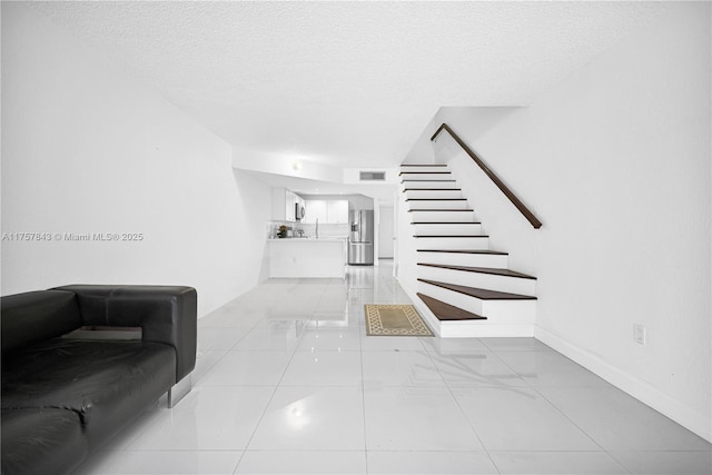 interior space featuring visible vents, baseboards, a textured ceiling, and tile patterned floors