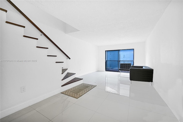 tiled living area featuring a textured ceiling, stairs, and baseboards