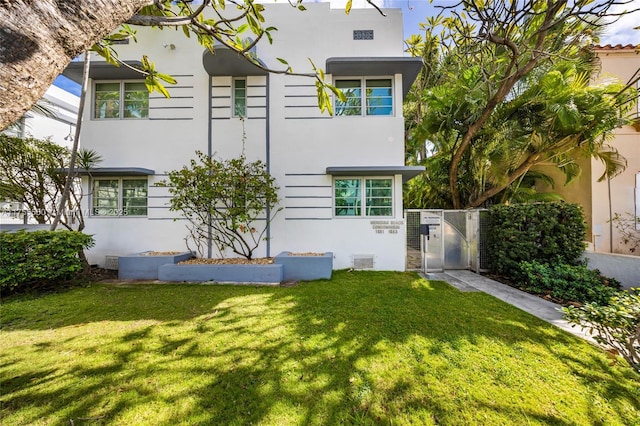 view of front of property with a gate, a front lawn, and stucco siding