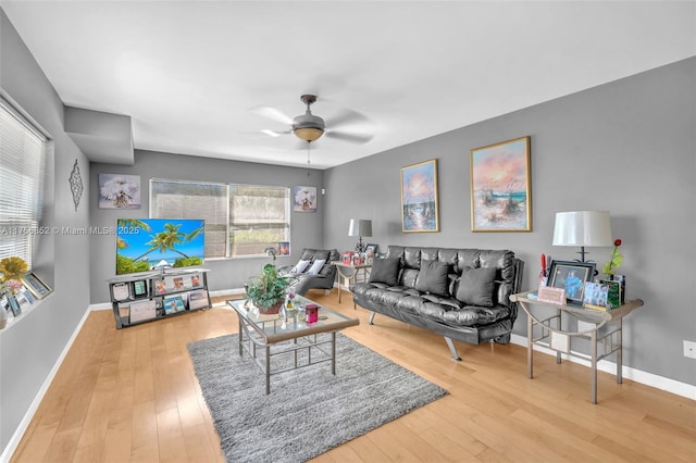 living area featuring ceiling fan, hardwood / wood-style floors, and baseboards