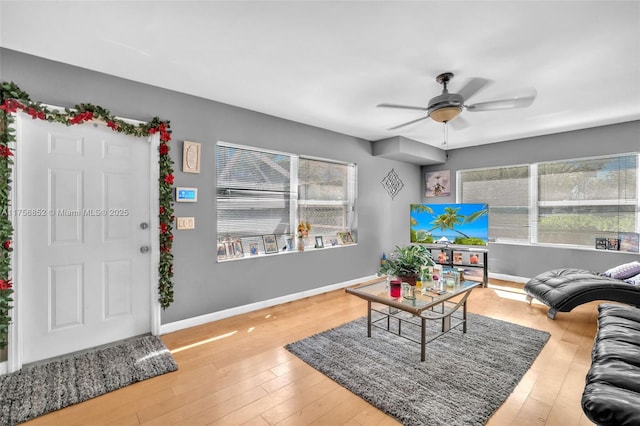 living area with a ceiling fan, baseboards, and hardwood / wood-style floors