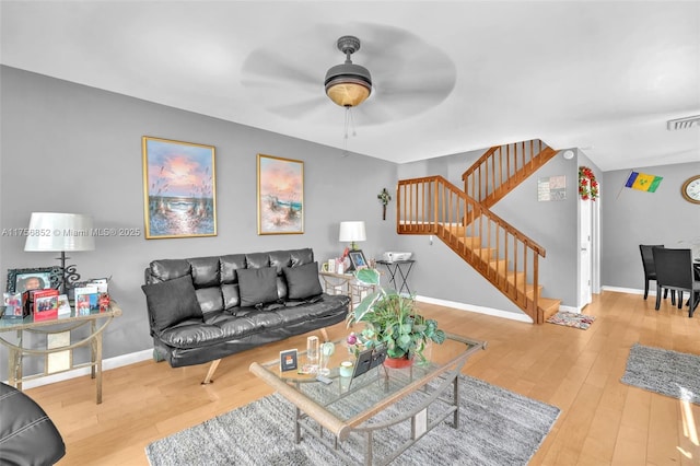 living area with stairs, wood-type flooring, visible vents, and baseboards