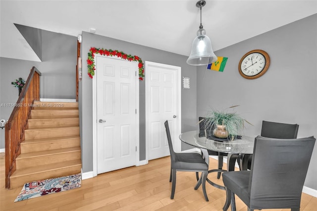 dining space with light wood-style flooring, stairway, and baseboards