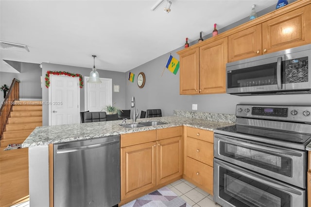 kitchen with light stone counters, light tile patterned flooring, a peninsula, a sink, and appliances with stainless steel finishes