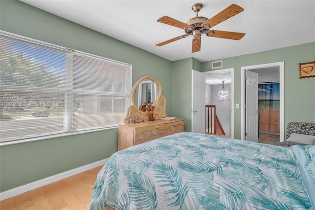 bedroom featuring baseboards, visible vents, a ceiling fan, connected bathroom, and wood finished floors