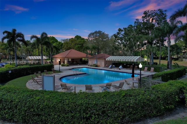 pool at dusk with a patio area, a gazebo, and a community pool