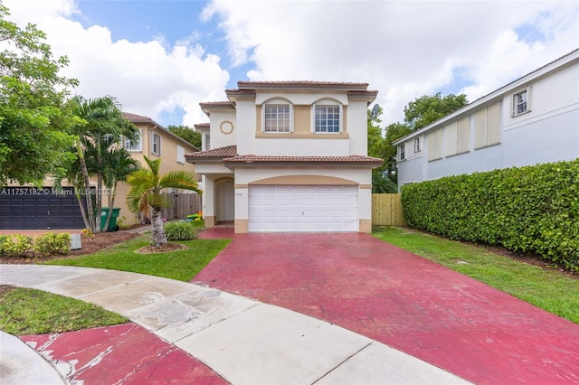 mediterranean / spanish-style home with decorative driveway, an attached garage, fence, and stucco siding