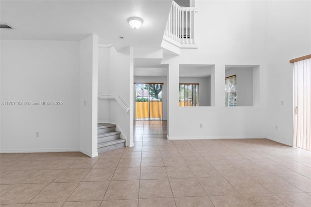 unfurnished room with stairway, light tile patterned flooring, visible vents, and baseboards