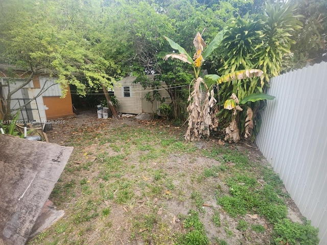 view of yard with a storage shed, a fenced backyard, and an outbuilding