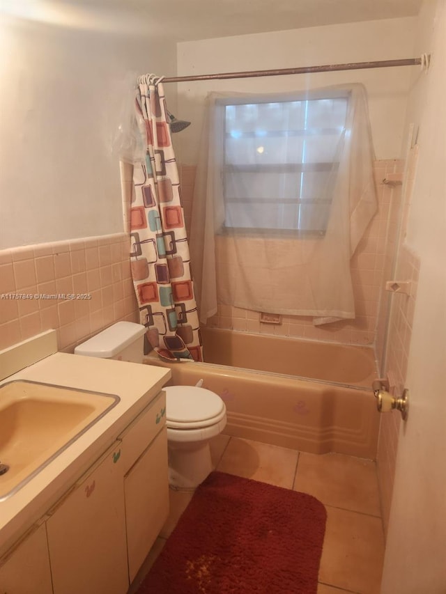 bathroom with tile patterned flooring, toilet, vanity, tile walls, and shower / tub combo with curtain