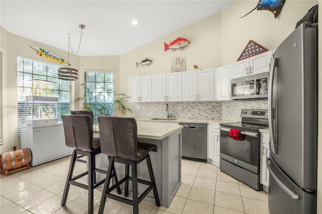 kitchen featuring tasteful backsplash, a breakfast bar area, stainless steel appliances, white cabinetry, and a sink