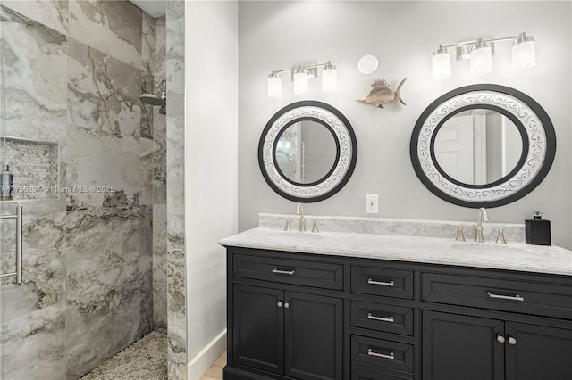 bathroom with double vanity, a marble finish shower, and a sink