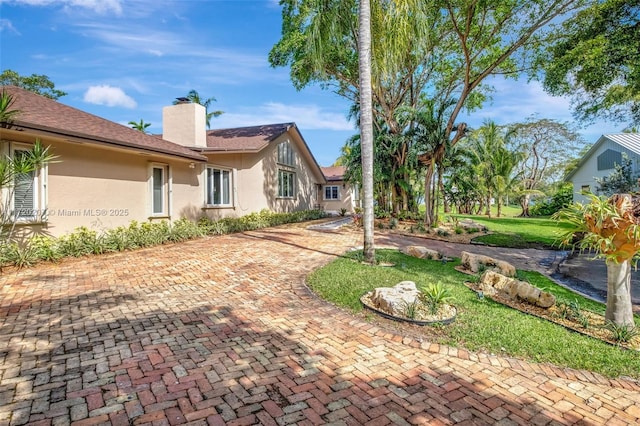 exterior space with a yard, a chimney, and stucco siding