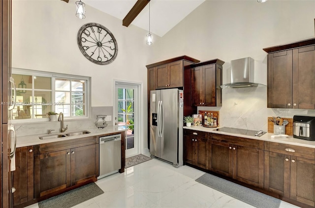 kitchen with light countertops, backsplash, appliances with stainless steel finishes, a sink, and wall chimney range hood