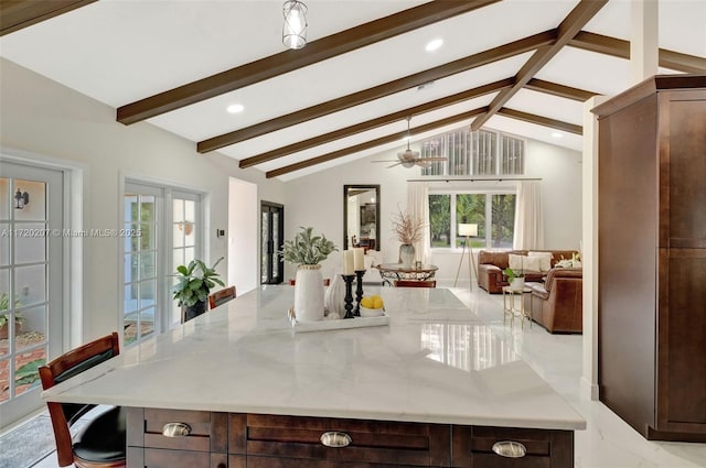 kitchen with light stone counters, a large island, lofted ceiling with beams, open floor plan, and dark brown cabinets