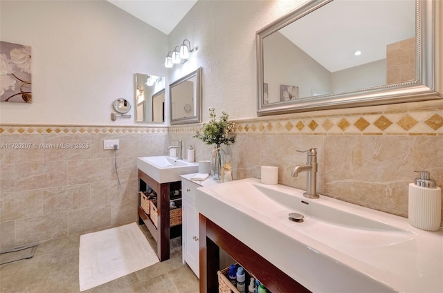 bathroom featuring tile walls, two vanities, a sink, and tile patterned floors