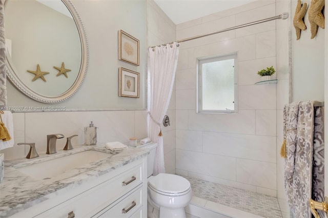 bathroom with tiled shower, vanity, and toilet