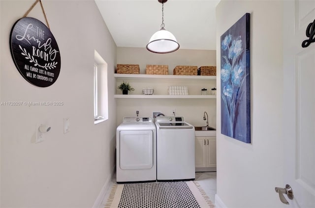 washroom featuring baseboards, a sink, cabinet space, and washer and dryer