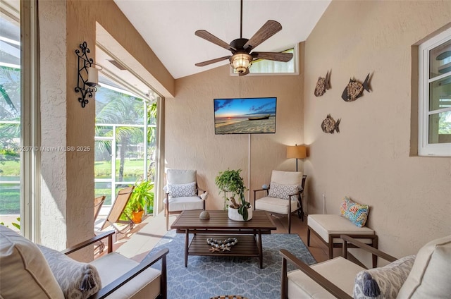 living room with a ceiling fan, vaulted ceiling, and a textured wall