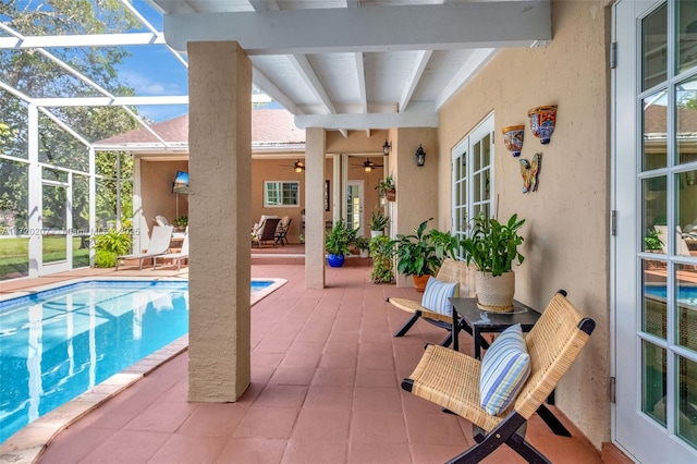 pool with glass enclosure, ceiling fan, and a patio