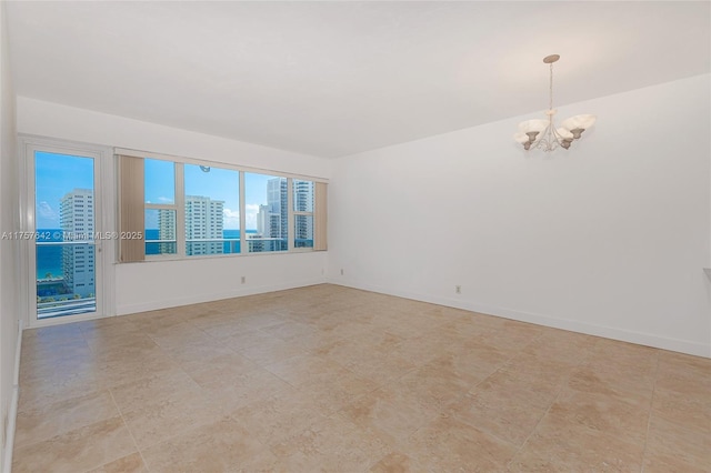 unfurnished room with a chandelier, baseboards, and a city view