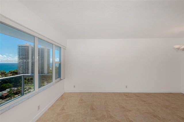 unfurnished room with a healthy amount of sunlight, a water view, and baseboards