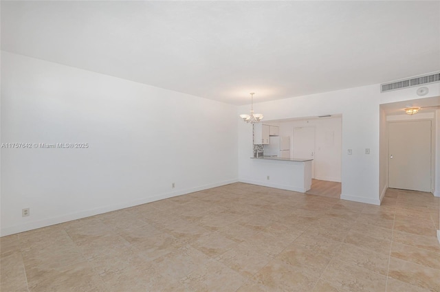 empty room with visible vents, a notable chandelier, and baseboards