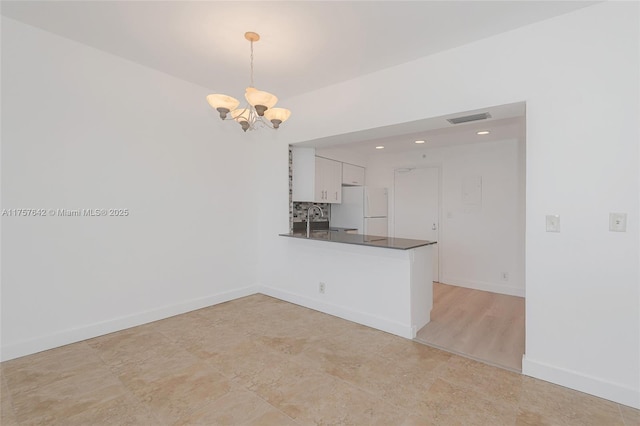 kitchen featuring dark countertops, visible vents, freestanding refrigerator, white cabinetry, and a sink