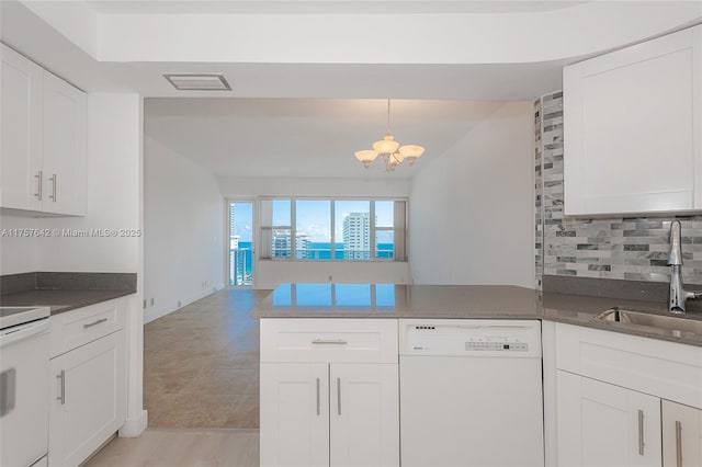 kitchen with visible vents, electric range oven, a peninsula, white dishwasher, and a sink