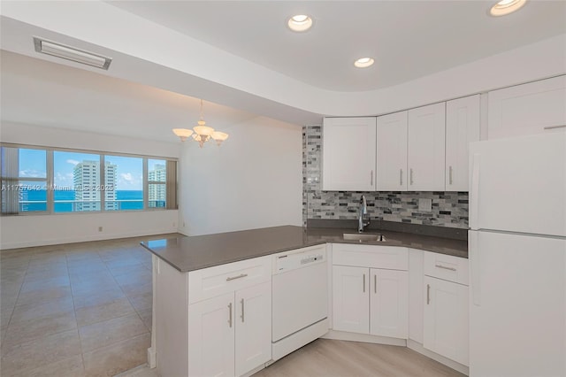 kitchen with dark countertops, visible vents, backsplash, a sink, and white appliances